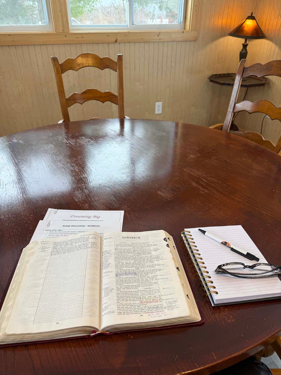 An open Bible and notebook on a cabin table
