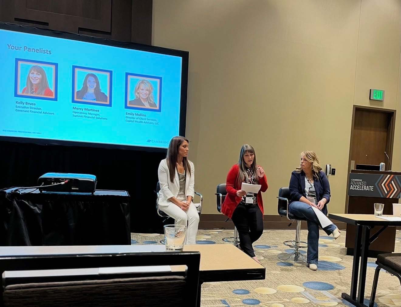 Kelly Bruce speaking on a conference panel with two other panellists
